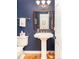 Stylish powder room with blue walls, pedestal sink, and wood-framed mirror at 6964 S Olive Way, Centennial, CO 80112