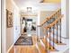 Elegant foyer featuring hardwood floors, a patterned rug, and staircase with rod iron spindles at 6964 S Olive Way, Centennial, CO 80112