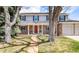 Charming two-story home with brick facade, red front door, and landscaped front yard with mature trees at 6964 S Olive Way, Centennial, CO 80112