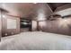 Basement features brown walls and ceiling, with gray carpeting and a wall-mounted television at 1007 Thorncreek Ct, Thornton, CO 80241