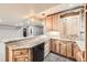 Basement kitchen features light wood cabinets, granite counters, a sink, and a black dishwasher at 1007 Thorncreek Ct, Thornton, CO 80241