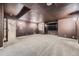 Basement features brown walls and ceiling, with gray carpeting and sconce lighting at 1007 Thorncreek Ct, Thornton, CO 80241