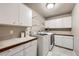 Functional laundry room with washer, dryer, white cabinets, and countertops for folding clothes at 1007 Thorncreek Ct, Thornton, CO 80241