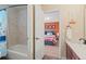 Bathroom featuring a shower over tub combination and doorway view to a bedroom with bright orange walls at 9468 E Aspen Hill Ln, Lone Tree, CO 80124