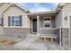 Lovely, covered front porch with stone accents, white railing, and a welcoming bench seating area at 6766 Mentha Dr, Castle Rock, CO 80108