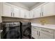 Bright laundry room with new front-load washer and dryer, storage cabinets, and a sink at 6766 Mentha Dr, Castle Rock, CO 80108