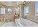 Relaxing bathroom with soaking tub, glass shower, and neutral tiled surround at 15235 W Iliff Ave, Lakewood, CO 80228