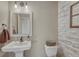 Charming powder room featuring a pedestal sink, stylish mirror, and decorative wood paneling at 15235 W Iliff Ave, Lakewood, CO 80228
