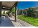 Spacious covered patio with stone pillars and backyard with mature trees and lush green lawn at 15235 W Iliff Ave, Lakewood, CO 80228