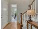 Hallway with wood floors, staircase, and view into a bright living room with comfortable seating at 15235 W Iliff Ave, Lakewood, CO 80228
