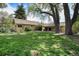 Large grassy backyard with mature trees and a view of the home's exterior under a blue sky at 895 Vance St, Lakewood, CO 80214
