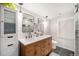 Modern bathroom with double sinks, a wood vanity, and a sleek, tiled shower at 895 Vance St, Lakewood, CO 80214