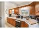 A well-lit kitchen boasts wood cabinets and white tile counters with a double basin sink under a window at 895 Vance St, Lakewood, CO 80214