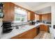A well-lit kitchen boasts wood cabinets, white tile counters, and a double basin sink under a window at 895 Vance St, Lakewood, CO 80214