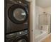 Bathroom featuring a stacked washer and dryer next to a shower and tub at 13456 Via Varra # 208, Broomfield, CO 80020