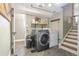 A modern laundry room featuring a gray front-load washer and dryer, shelving, and stylish herringbone flooring at 3326 S Geneva St, Denver, CO 80231
