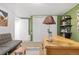 A bright home office space with a wooden desk, decorative shelves, closet and a comfortable gray futon at 3326 S Geneva St, Denver, CO 80231