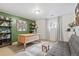 A bright home office space with a wooden desk, decorative shelves, and a comfortable gray futon at 3326 S Geneva St, Denver, CO 80231