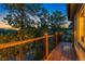 A well-lit, wooden deck features dark railings, and is framed by mature pine trees and a setting sun at 150 Hess Ave, Golden, CO 80401