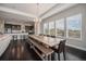 Dining area with a long wooden table and bench seating adjacent to a modern kitchen with barstools at 23440 E Rockinghorse Pkwy, Aurora, CO 80016