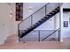 Modern staircase featuring wooden steps and a sleek black metal railing, illuminated by stylish wall sconces at 5125 W 29Th Ave # 1, Denver, CO 80212