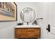 Modern powder room featuring a sleek vanity with a round mirror, stylish decor, and unique artwork at 937 Aztec Dr, Castle Rock, CO 80108