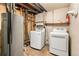 Unfinished basement features a hot water heater, modern white washer and dryer, and exposed utilities at 6185 Sheridan Blvd, Arvada, CO 80003