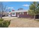 Red brick home with a well-kept lawn, an attached garage, and a quaint front entrance at 6185 Sheridan Blvd, Arvada, CO 80003