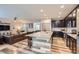 Open-concept kitchen features dark cabinets, a granite island with seating, and views into the living room at 6883 E 132Nd Pl, Thornton, CO 80602