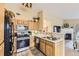 Well-lit kitchen with wood cabinets, a stainless steel range, and views into the adjacent living room at 8334 Pebble Creek Way # 201, Highlands Ranch, CO 80126