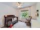 Bright bedroom featuring a crib, rocking chair, and large window with natural light at 728 Poppywood Pl, Highlands Ranch, CO 80126