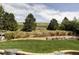 Landscaped backyard featuring a retaining wall, lush green grass, and mature trees for added privacy at 6123 Dunraven Rd, Golden, CO 80403