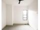 An empty bedroom shows neutral carpet, a black fan, base moulding, and a black framed window at 2751 Curtis St, Denver, CO 80205