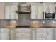 A stylish kitchen features white cabinets, stainless steel appliances, and a mosaic tile backsplash at 8951 Greenwich St, Highlands Ranch, CO 80130