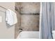 Close-up of a tub and shower with tile surround featuring decorative tile accents and shower head at 2397 E Iliff Ave, Denver, CO 80210