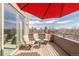 This deck features chairs and a table, and is shaded by a red umbrella at 2397 E Iliff Ave, Denver, CO 80210