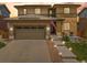 Beautiful home exterior at sunset, showcasing the well-lit walkway and American flag at 10906 Touchstone Loop, Parker, CO 80134