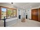 A soaking tub sits beneath a picture window, alongside a frameless glass shower at 6330 Old Orchard Ln, Sedalia, CO 80135