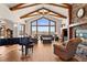 Inviting living room features vaulted ceilings, wood beams, stone fireplace, piano, and expansive views at 6330 Old Orchard Ln, Sedalia, CO 80135