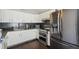 Modern kitchen with stainless steel appliances, white cabinets, granite counters, and a sleek dark backsplash at 21111 E 43Rd Ave, Denver, CO 80249