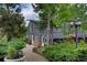 Picturesque exterior view of a barn-style home with lush landscaping and a winding brick walkway at 97 Soda Creek Rd, Evergreen, CO 80439