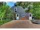 Charming barn-style home with gray siding, brick foundation, and a paved driveway lined with trees at 97 Soda Creek Rd, Evergreen, CO 80439