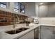 Modern kitchen with granite countertops, brick backsplash, stainless sink, and white cabinetry at 97 Soda Creek Rd, Evergreen, CO 80439