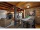 Open-concept living area featuring a wooden dining table, exposed beams, and comfortable leather armchairs at 97 Soda Creek Rd, Evergreen, CO 80439