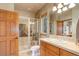 Well-lit bathroom with a glass-enclosed shower, neutral tile, wood cabinets, and a bright vanity area at 12825 W 81St Ave, Arvada, CO 80005