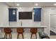 A bar with accent lighting, navy blue cabinets, and a flat screen television at 14841 W Warren Ave, Lakewood, CO 80228