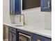 Elegant wet bar boasts navy cabinets, white counters, gold hardware, and stainless steel appliances at 14841 W Warren Ave, Lakewood, CO 80228