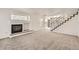 Open living room with a fireplace, staircase, and neutral carpeting creating a cozy atmosphere at 20000 E Mitchell Pl # 34, Denver, CO 80249