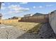 Large backyard featuring a wooden fence, rock landscaping, and dry grass under a blue sky at 8852 Ventura St, Commerce City, CO 80022