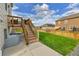 A lush green backyard with a well-maintained lawn and a set of stairs leading to the back deck at 562 Gallo St, Brighton, CO 80603